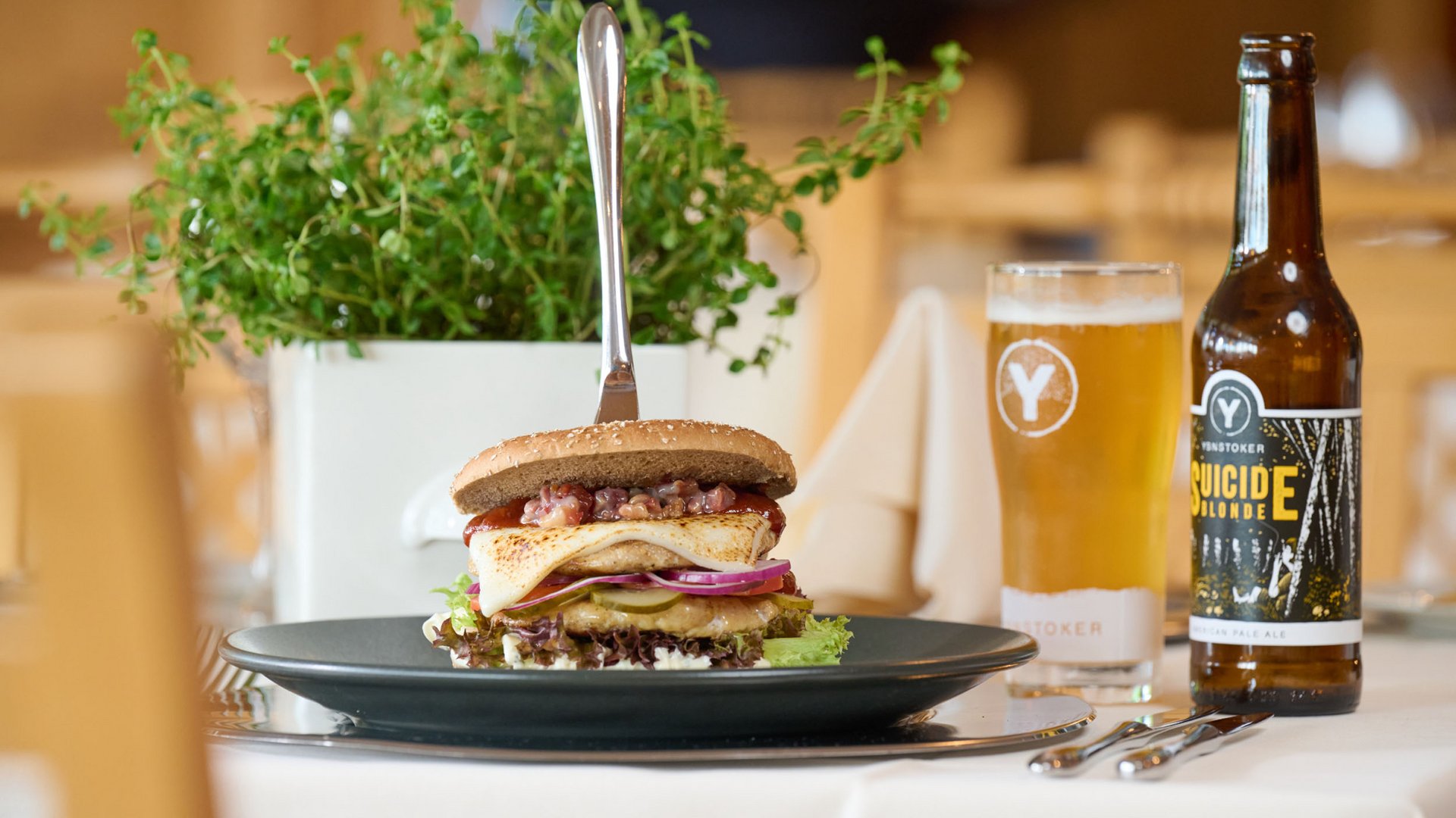 Burger mit Gemüse und Bier auf einem gedeckten Tisch