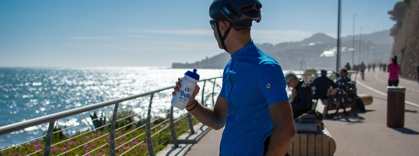 Cyclist resting by the sea holding a water bottle