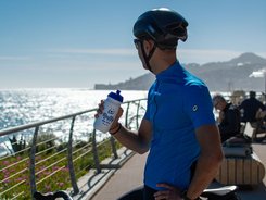 Radfahrer macht Pause am Meer und hält eine Trinkflasche