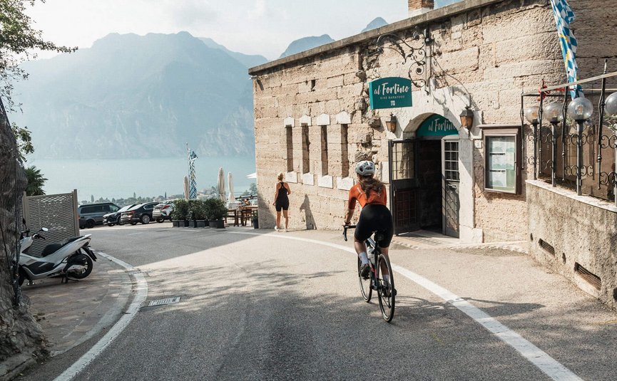 Fahrradfahrer auf Straße neben altem Steinbau in bergiger Landschaft