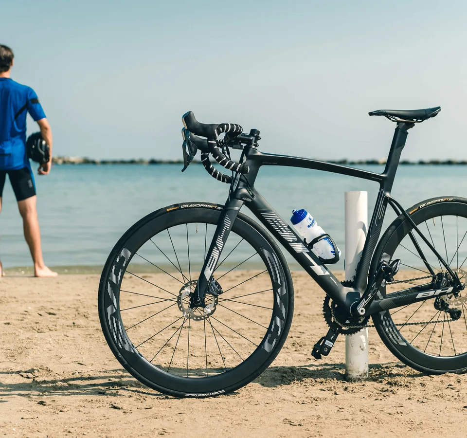 Saisonstart am Meer © Alex Moling Schwarzes Rennrad am Strand, Radfahrer blickt aufs Meer