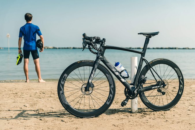 Schwarzes Rennrad am Strand, Radfahrer blickt aufs Meer