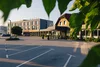 Collectief onderzoek © Ziga Intihar Hotelgebouw met parkeerplaats en groene bladeren op de voorgrond
