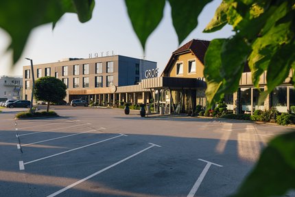 Hotelgebouw met parkeerplaats en groene bladeren op de voorgrond