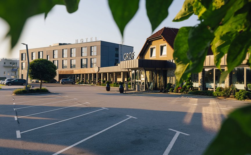 Edificio dell'hotel con parcheggio e foglie verdi in primo piano