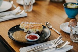 Stück Kuchen mit Soße und Marmelade auf schwarzem Teller auf Holztisch