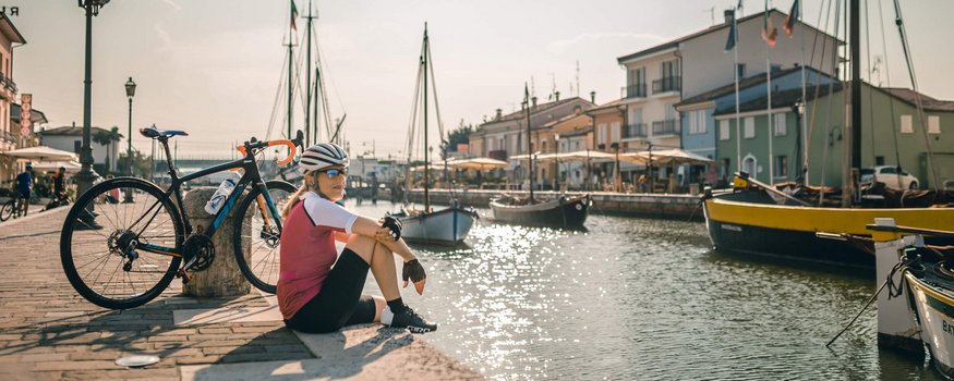 Cyclist sitting by the harbor with boats and bike in the sunlight