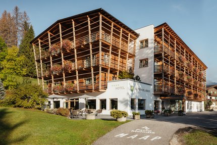 Hotel Melodia del Bosco with wooden balconies and flowers in a sunny mountain setting