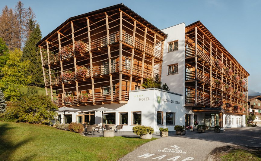 Hotel Melodia del Bosco con balconi in legno e fiori in ambiente montano soleggiato
