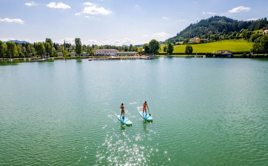 Two people paddleboarding on a calm lake on a sunny day