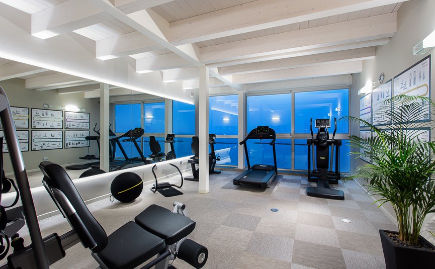 Modern gym room with exercise machines and large mirrors