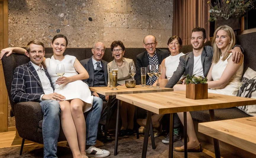 Fröhliche Familie sitzt zusammen auf einem Sofa mit Getränken im Wohnzimmer