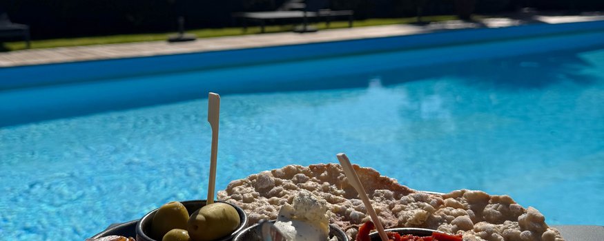 Vorspeisenteller mit Schinken, Oliven, Käse und Brot neben einem Pool