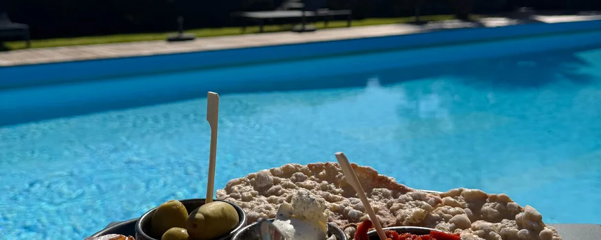 Appetizer plate with ham, olives, cheese, and bread by the pool
