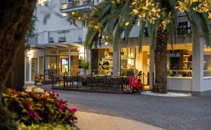 Area esterna del ristorante con scooter rossi e palme al crepuscolo