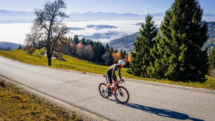 Cyclist riding on mountain road with foggy valley and mountains in background