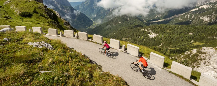 Zwei Radfahrer auf Bergstraße mit Blick auf Berge und Wolken
