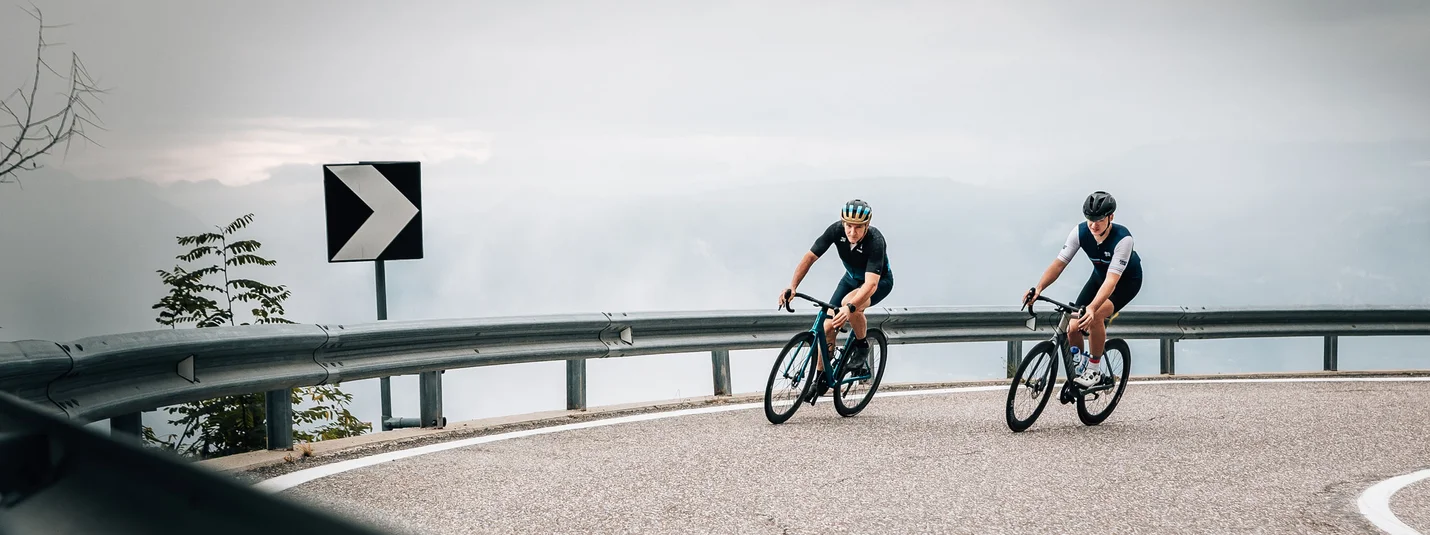 Rennrad Urlaub in Sterzing © Jens Scheibe Zwei Radfahrer fahren auf einer kurvigen Bergstraße bei bewölktem Himmel
