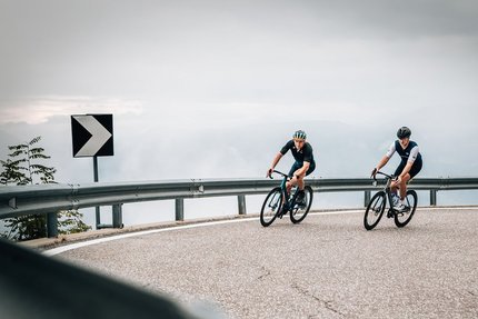 Sterzing © Jens Scheibe Zwei Radfahrer fahren auf einer kurvigen Bergstraße bei bewölktem Himmel