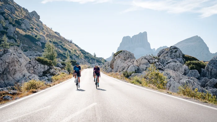 3 Rennrad-Passklassiker rund um Cortina © Josef Plaickner Zwei Radfahrer fahren auf Bergstraße mit Felsen und Gipfeln im Hintergrund