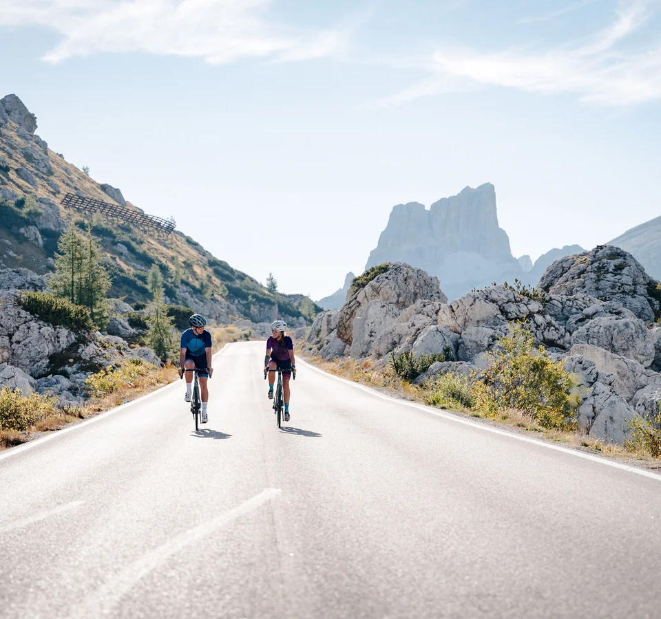 Best of Roadbike in Cortina d’Ampezzo © Josef Plaickner Zwei Radfahrer fahren auf Bergstraße mit Felsen und Gipfeln im Hintergrund
