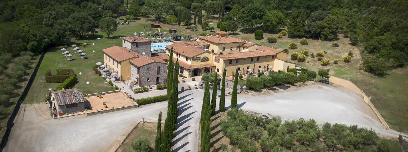 Door de Valdelsa Senese en de Montagnola Senese © Hotel Casolare Le Terre Rosse Luchtfoto van een landhuis met zwembad omgeven door bomen en olijfgaard