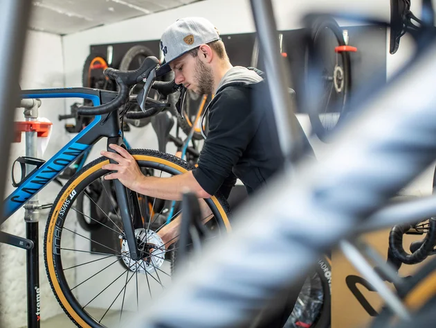 Ein Rennrad-Wochenende im SalzburgerLand – Salzkammergut © Erwin Haiden Mann repariert Rennrad in Fahrradwerkstatt mit grauer Kappe
