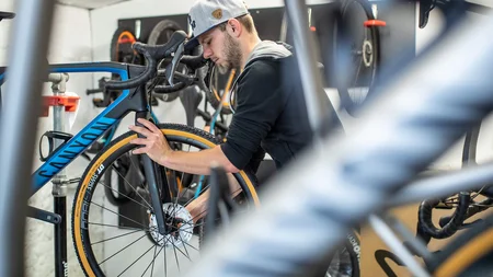 Ein Rennrad-Wochenende im SalzburgerLand – Salzkammergut © Erwin Haiden Mann repariert Rennrad in Fahrradwerkstatt mit grauer Kappe