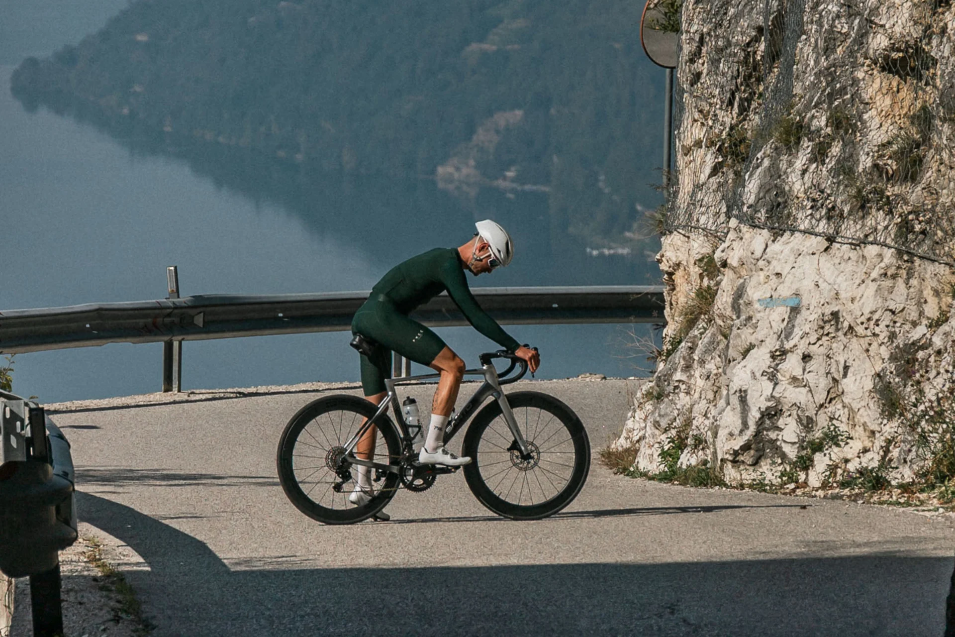 Radfahrer fährt auf bergiger Straße nahe Tunnel mit Seeblick