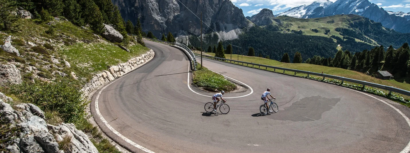 Giau Pass Tour © Paola Finali Radfahrer fahren enge Haarnadelkurve in bergiger Landschaft bei klarem Himmel