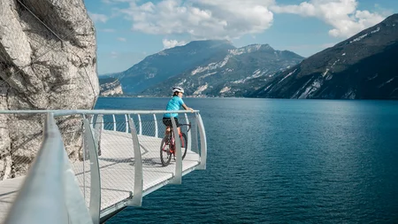 Die schönsten Rennrad-Regionen und Tipps für den Herbst © Alex Moling Radfahrer auf Steg mit Blick auf See und Berge bei sonnigem Wetter