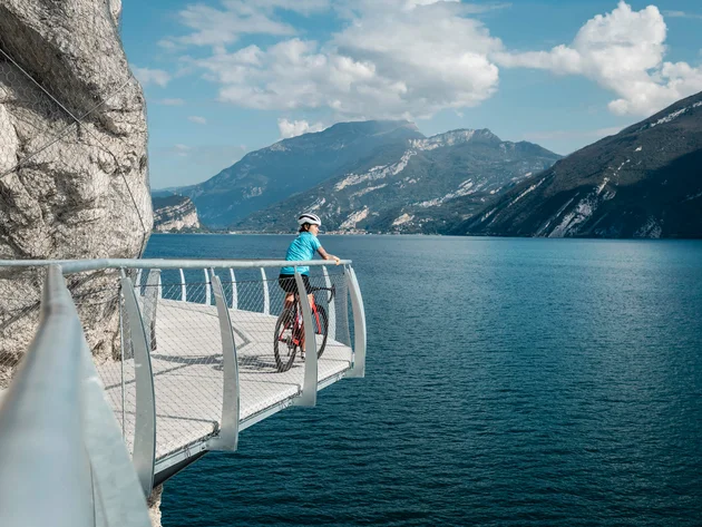 Die schönsten Rennrad-Regionen und Tipps für den Herbst © Alex Moling Radfahrer auf Steg mit Blick auf See und Berge bei sonnigem Wetter