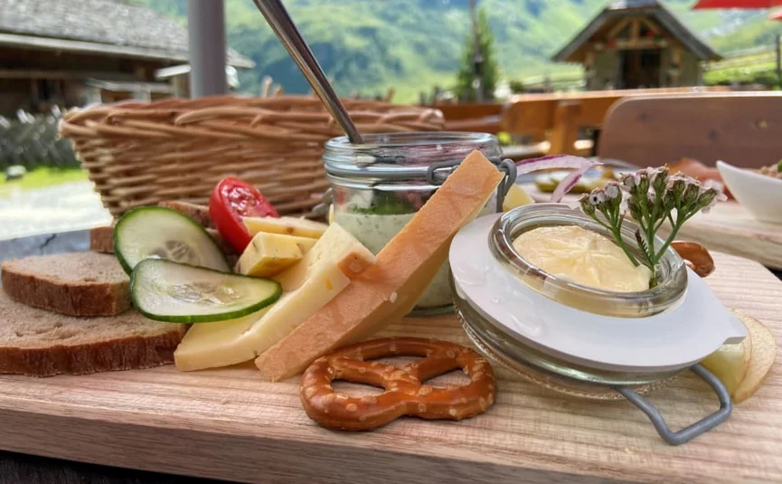 Pane, formaggio, verdure e salse serviti su un tagliere all'aperto