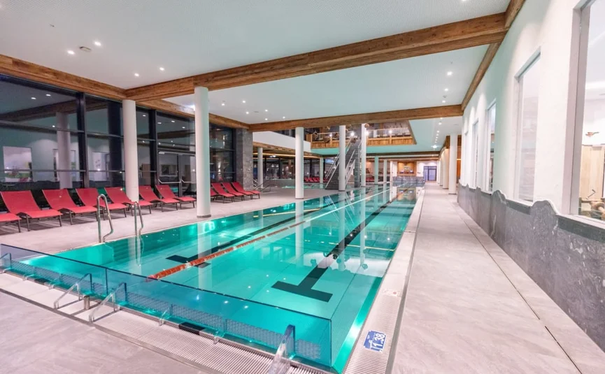 Innenraum eines modernen Schwimmbads mit roten Liegestühlen