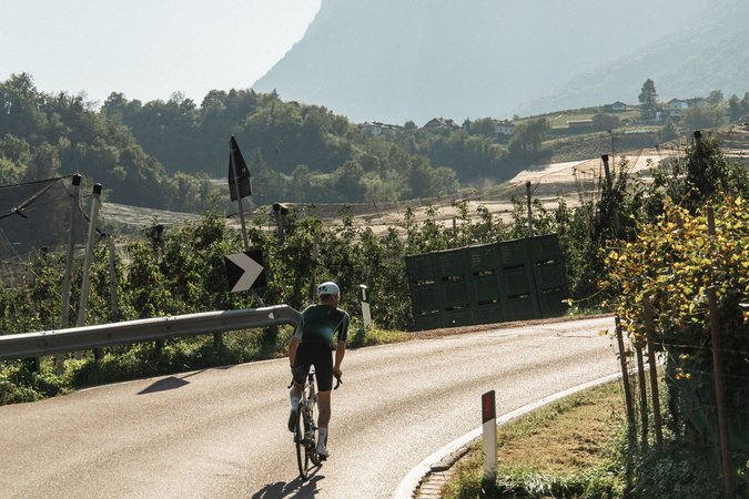 Radfahrer auf einer kurvigen Landstraße mit Bergen im Hintergrund