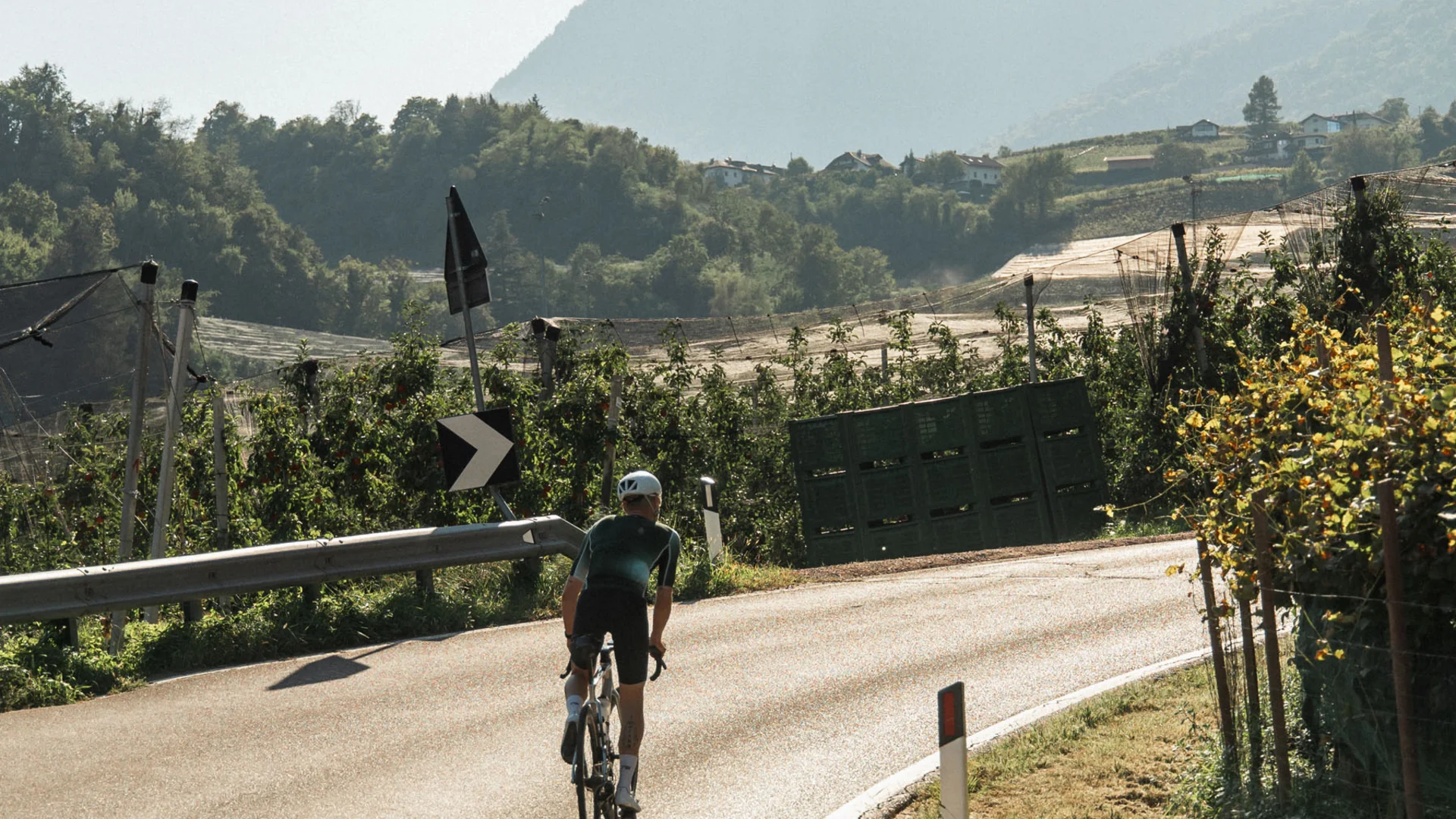 Cyclist on a winding country road with mountains in the background