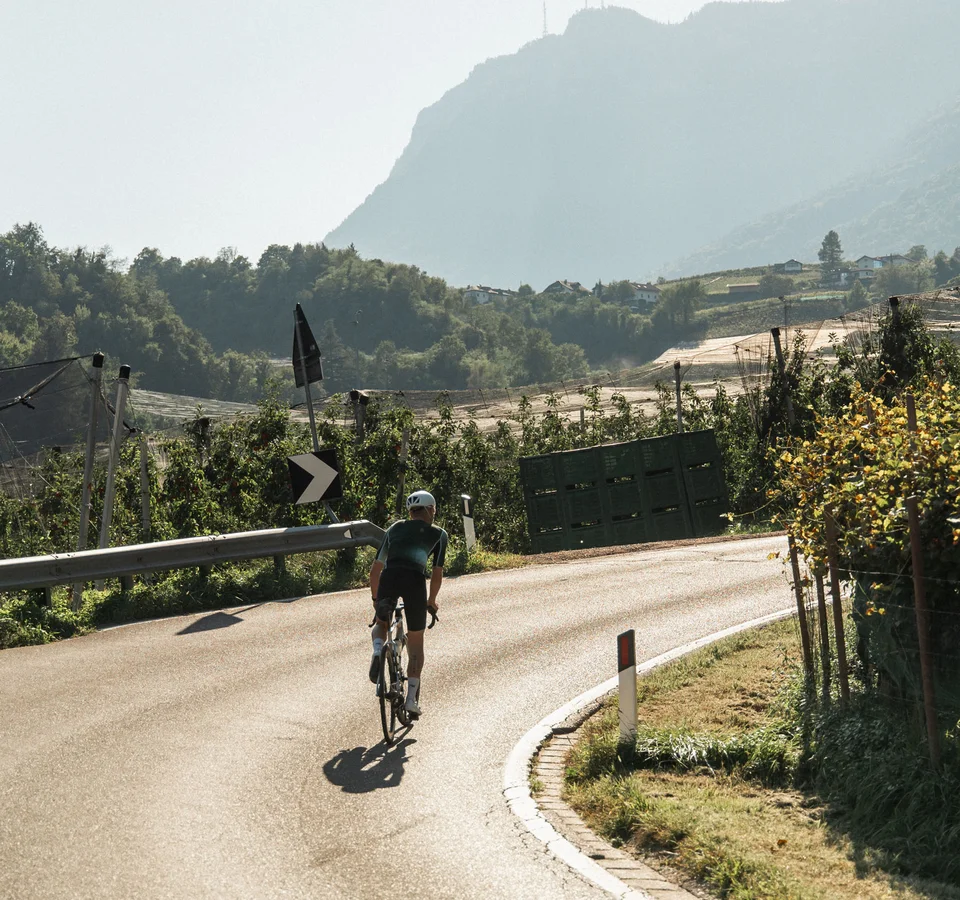 Cyclist on a winding country road with mountains in the background