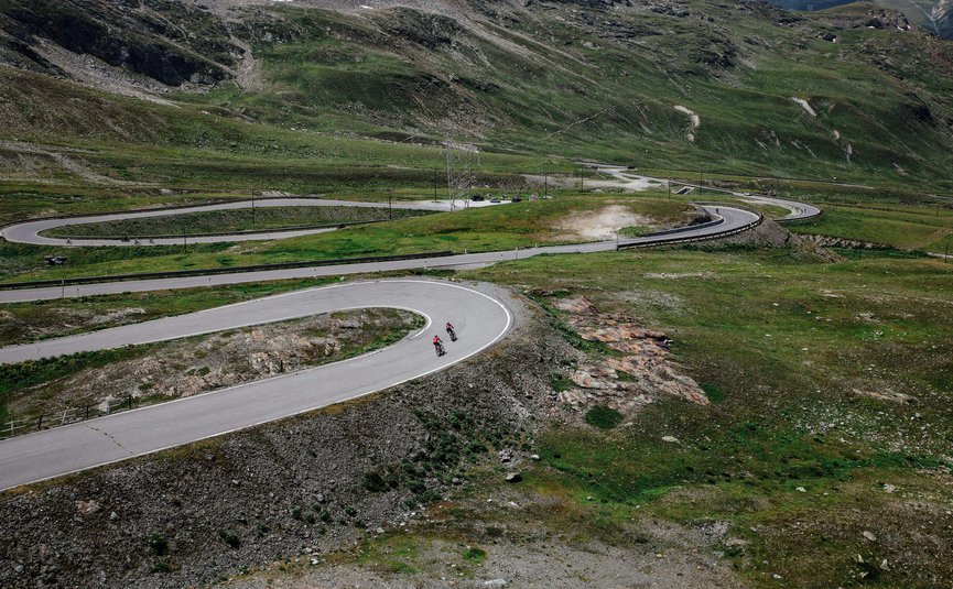 Twee fietsers op kronkelende bergweg door groen landschap