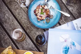 Tisch mit Dessert, Pizza, Getränken, Büchern und einer Schale roter Früchte