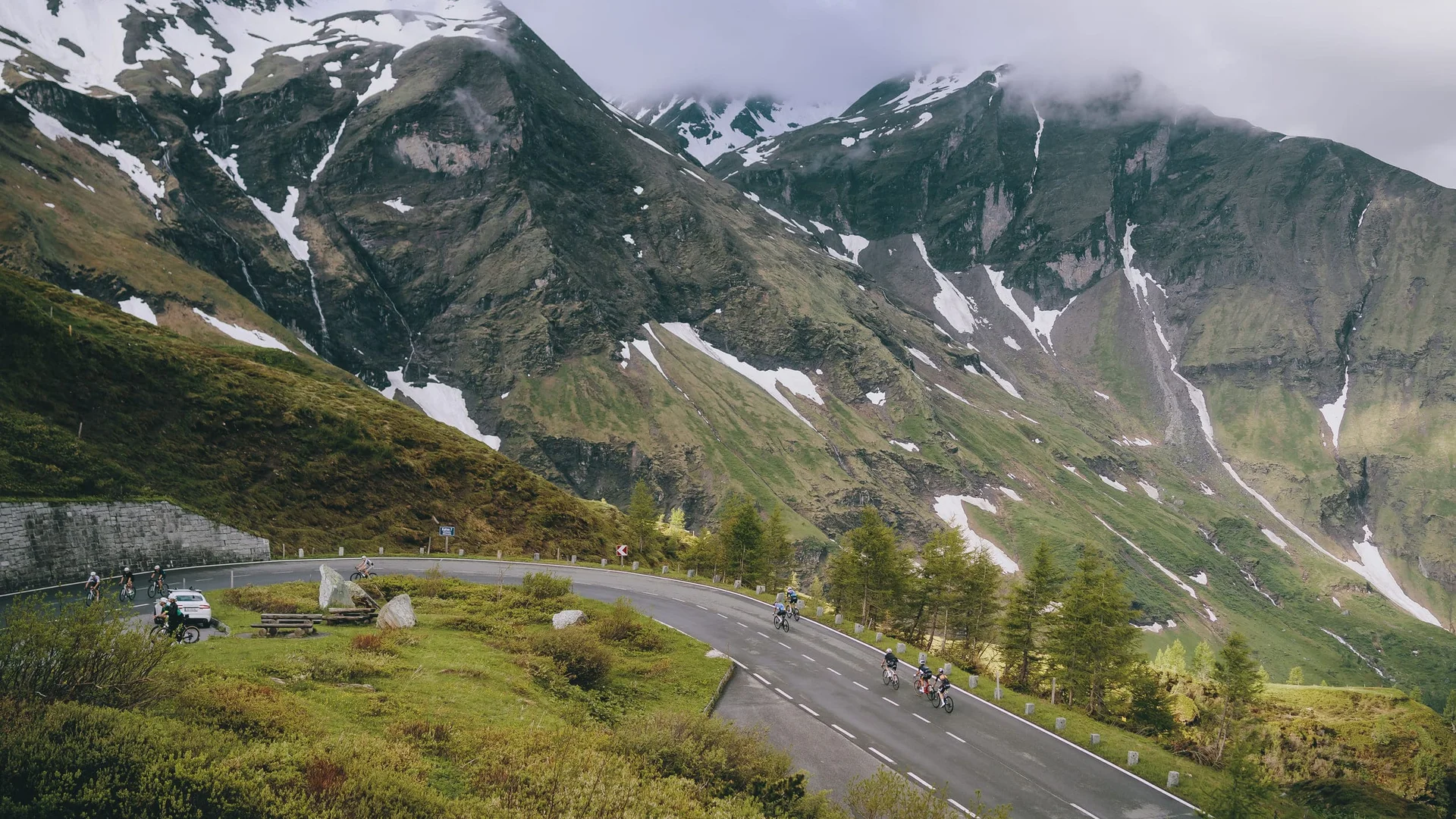 Glocknerkönig 2026 © BRUCK FUSCH GROSSGLOCKNER JFK Photography Fahrradfahrer auf kurviger Bergstraße mit schneebedeckten Gipfeln im Hintergrund
