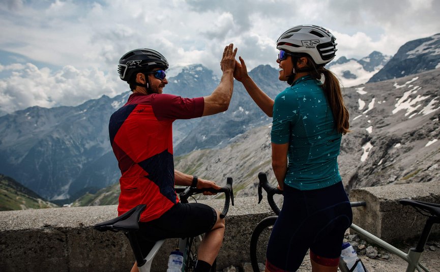 Two cyclists high-fiving on a mountain road
