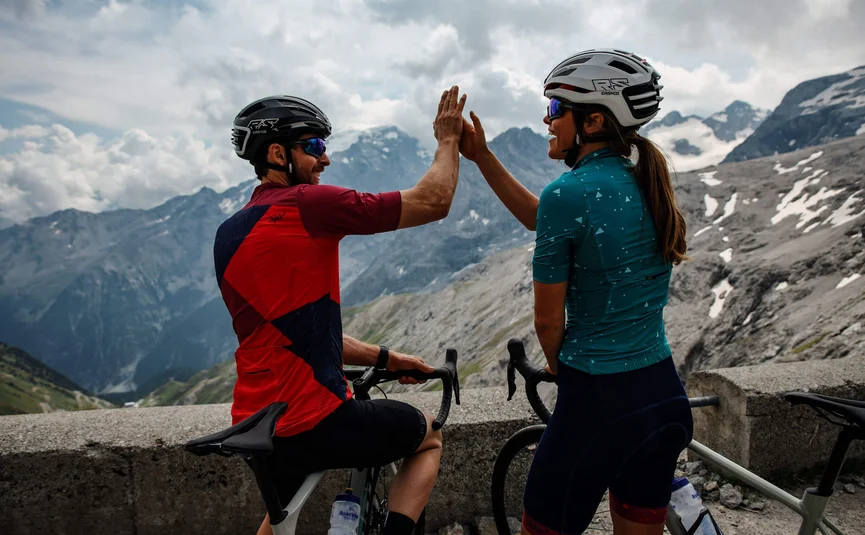 Due ciclisti si danno il cinque in montagna