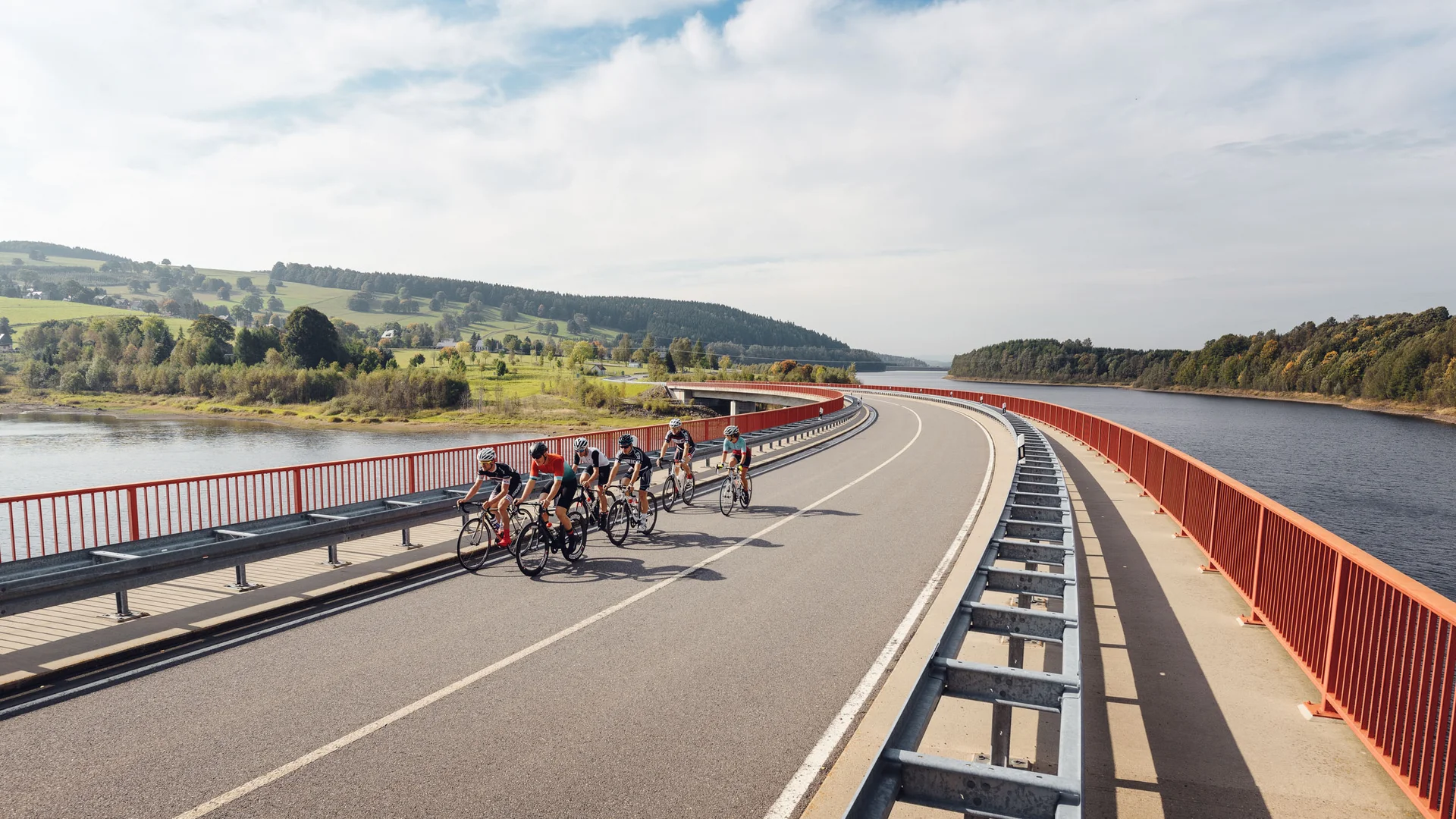 Racefietsen als groep © Felix Meyer Groep fietsers rijdt over brug naast rivier en groen landschap
