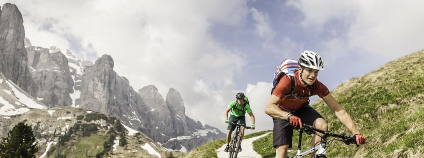 Two mountain bikers riding on a trail in the Alps.