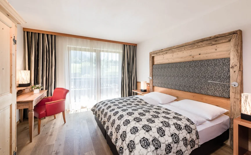 Helles Schlafzimmer mit großem Bett, Holzdekor und rotem Stuhl