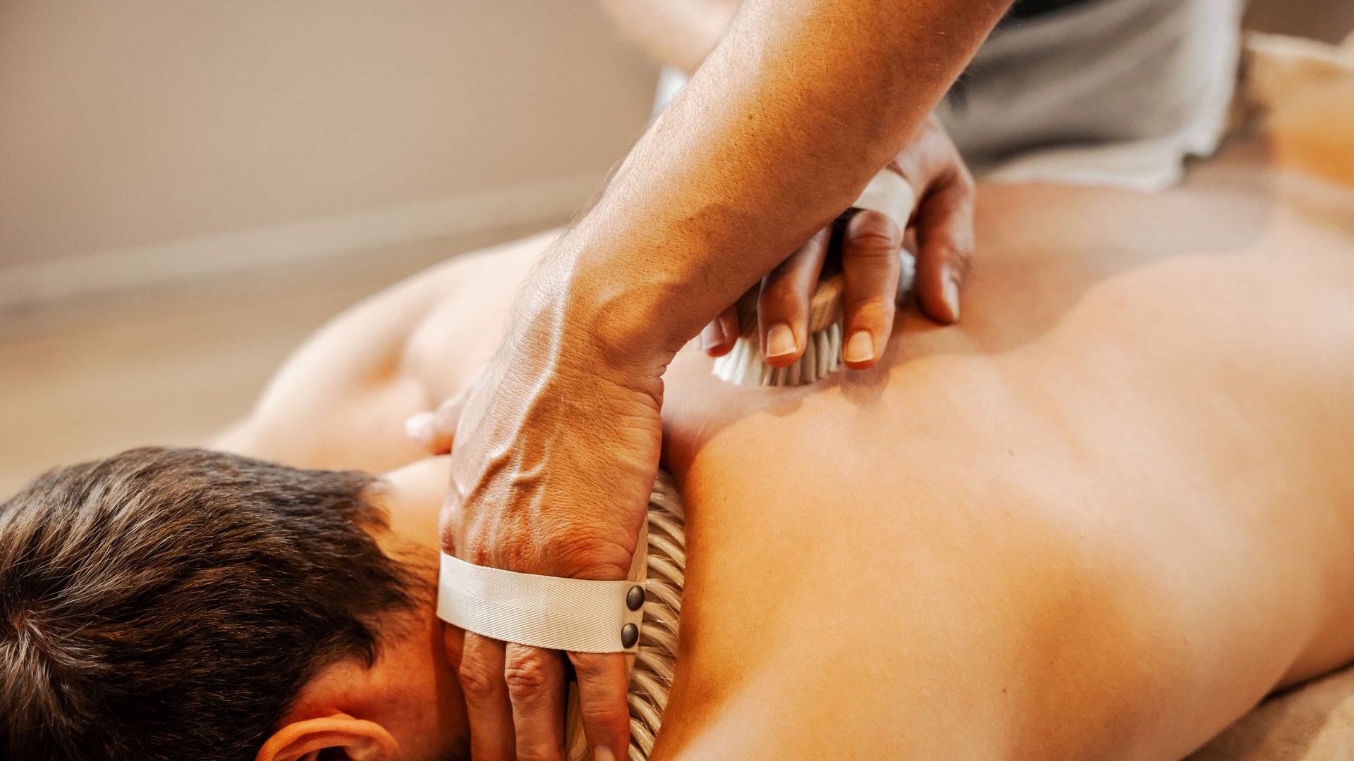 Mann bekommt Rückenmassage mit Massagebürste