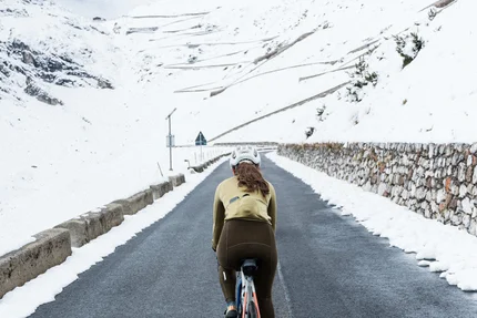 Radfahrerin auf bergiger Straße mit Schnee an den Seiten