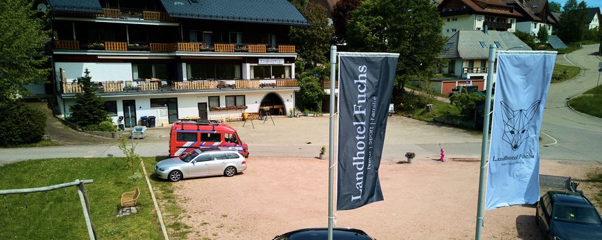 Landhotel Fuchs mit Parkplatz, Fahnen und angrenzendem Kinderspielplatz