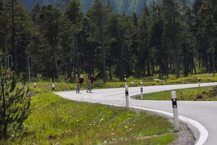 Due ciclisti su una strada tortuosa in una foresta