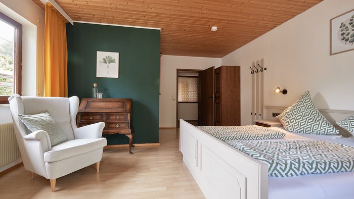 Gemütliches Schlafzimmer mit Holzmöbeln und grün-weißem Bettbezug